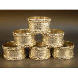 SET OF SIX SILVER CIRCULAR NAPKIN RINGS WITH FLORAL ENGRAVING, EACH MONOGRAMMED, BY JOHN ROSE,