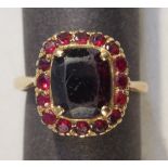 A 9ct GOLD RING SET WITH A LARGE CUSHION GARNET SURROUNDED BY 16 SMALLER STONES, RING SIZE T (3.5g