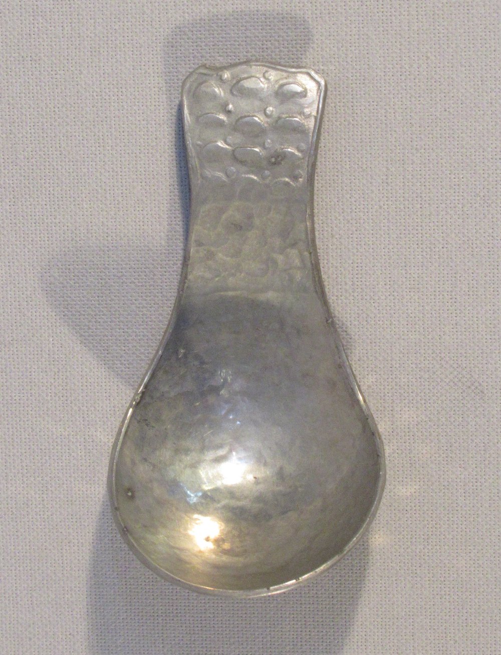 A METAL ARTS & CRAFTS HAMMERED CADDY SPOON, STAMPED ON BACK 'GWG' (L:7.2 cm)