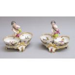 A NEAR PAIR OF BERLIN PORCELAIN DOUBLE SALT CELLARS, EACH MOUNTED WITH A PUTTO (H: 12.5cm) [2]