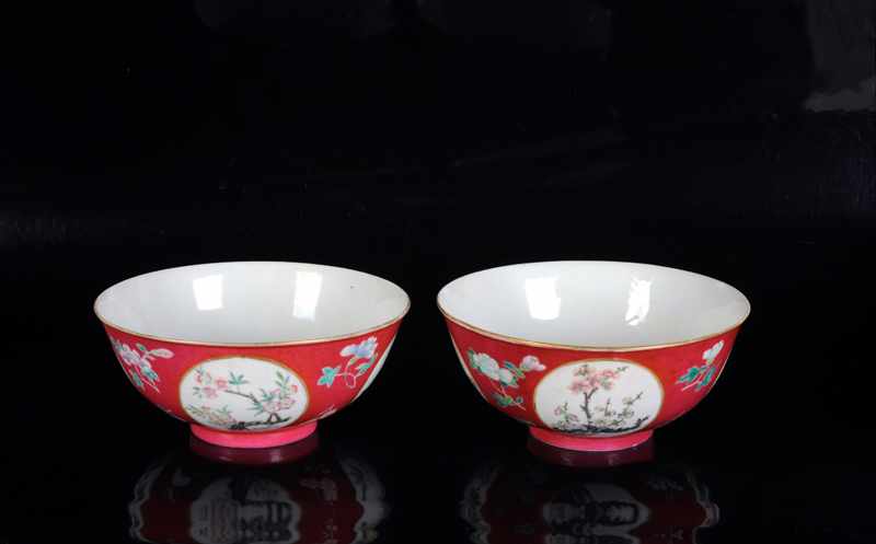 A pair of red porcelain medallion bowls with a decor of flowers. Marked with seal mark Qianlong.