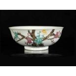 A polychrome porcelain bowl with a decor of prunus branches and characters. Marked with seal mark