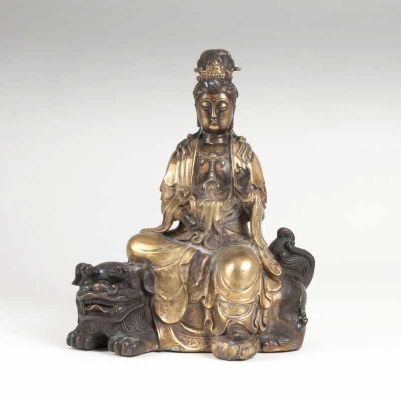 Bronzeskulptur 'Guanyin auf einem Löwen' China. Bronze, partiell vergoldet und braun patiniert.