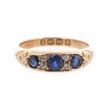 A SAPPHIRE RING set to the centre with three circular mixed-cut sapphires, embellished with four