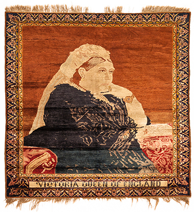 A TURKISH SILK RUG, CIRCA 1900 the madder-red field with an image of Queen Victoria, narrow floral