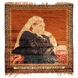 A TURKISH SILK RUG, CIRCA 1900 the madder-red field with an image of Queen Victoria, narrow floral