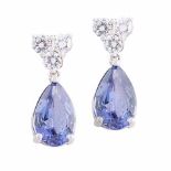 A PAIR OF TANZANITE AND DIAMOND EARRINGS each of articulated design, the surmount highlighted by a