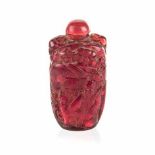 A CHINESE PEKING GLASS SNUFF BOTTLE of deep red tone, one side carved with 'Shou Lao' tending a