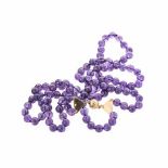 A DOUBLE STRAND AMETHYST BEAD NECKLACE composed of circular amethyst beads, the 18ct gold ball clasp