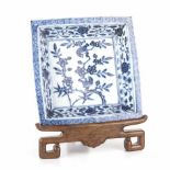 A CHINESE BLUE AND WHITE DISH, QING DYNASTY, 19TH CENTURY square, on a carved wooden stand the