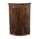 A MAHOGANY BOW-FRONTED HANGING CORNER CABINET, 19TH CENTURY the outswept pediment above a plain