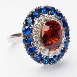 A MANDARIN GARNET, SAPPHIRE AND DIAMOND RING centred with an oval mixed-cut mandarin garnet weighing