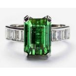 A GREEN TOURMALINE AND DIAMOND RING centered with a claw-set lozenge-cut green tourmaline weighing