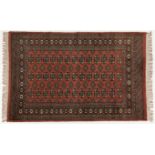 A PAKISTANI RUG, MODERN the rose field with three rows of guls and side guls depicted in ivory,