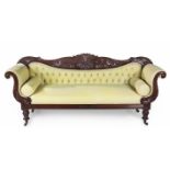A REGENCY MAHOGANY SETTEE the foliate-carved top rail above a padded button-back, stuff-over seat