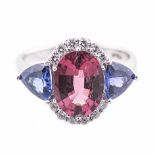 A PINK TOURMLAINE, TANZANITE AND DIAMOND RING centred with an oval mixed-cut pink tourmaline