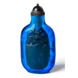 A CHINESE COBALT BLUE PEKING GLASS SNUFF BOTTLE on a short oval foot, the ovoid body carved with