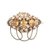 A CITRINE AND DIAMOND BROOCH/PENDANT composed of openwork scrolls, centred with three oval mixed-cut