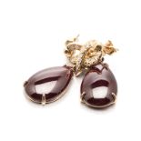 A PAIR OF GARNET AND DIAMOND PENDANT EARRINGS each ribbon-shaped surmount embellished with round