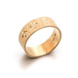 AN 18CT GOLD BAND with textured design, centred with diamond -set star detail, partially impressed
