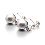 A PAIR OF PEARL AND DIAMOND EAR STUDS each surmount bezel-set with a round brilliant-cut diamond