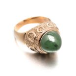 A JADE-LIKE STONE RING centred with a circular cabochon jade-like stone, the gallery with textured