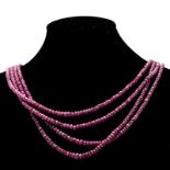 A RUBY BEAD NECKLACE composed of four strands of graduated faceted ruby beads weighing approximately