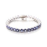 A TANZANITE BRACELET designed as a line of circular mixed-cut tanzanite's weighing approximately