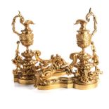 A PAIR OF LOUIS XV/LOUIS XVI TRANSITIONAL STYLE ORMOLU CHENETS each adorned with an ewer, above