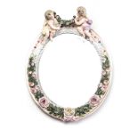 A MEISSEN STYLE MIRROR the oval plate within a conforming frame, adorned with rose buds and