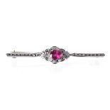 A RUBY BROOCH the thin bar with engraved detail centred with an oval mixed-cut ruby weighing