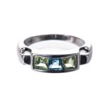 A PERIDOT AND BLUE TOPAZ RING channel-set to the centre with a princess-cut blue topaz, flanked on