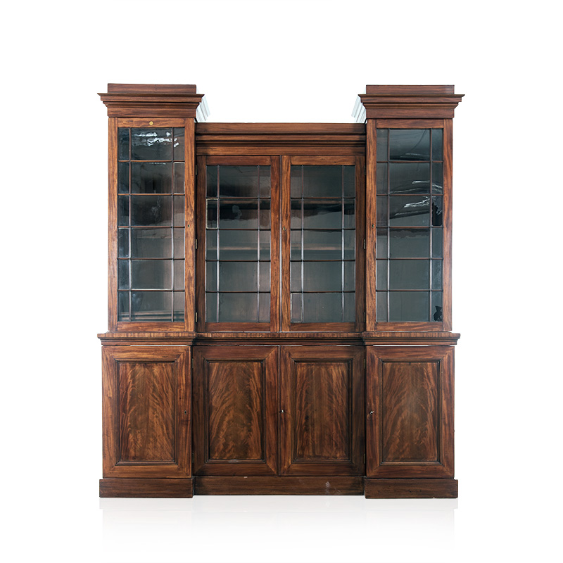 A FLAME MAHOGANY BREAKFRONT BOOKCASE, 19TH CENTURY in two parts, the outswept cornice above four