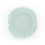 A CHINESE CELADON CHARGER circular, the interior moulded with floral decoration, covered overall