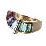 A GEMSTONE RING of undulating form, channel-set with various tapered baguette-cut gemstones,