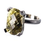 A LEMON QUARTZ AND DIAMOND RING centred with an oval faceted lemon quartz, the claws embellished