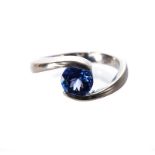 A TANZANITE RING, BROWNS the stylised band suspending a circular mixed-cut tanzanite weighing