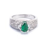 AN EMERALD AND DIAMOND RING centered with an oval mixed-cut emerald weighing approximately 0.