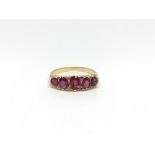 Five stone carved half hoop ring, graduating old red stones, with rose diamond detail, in yellow