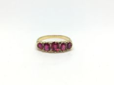 Five stone carved half hoop ring, graduating old red stones, with rose diamond detail, in yellow