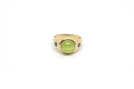 Peridot and sapphire ring, 10mm round cabochon peridot, set with a single sapphire to each side,