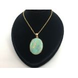 Opal pendant, oval cabochon opal measuring 22.8 x 30mm, in a yellow metal setting, on a yellow metal