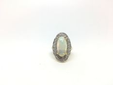 Opal and diamond ring, cabochon opal measuringg approximately 17 x 8.5mm, with a border of bombé set