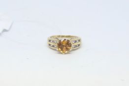Gem set ring, central orange stone with two rows of blue stones to each shoulder, ring size L
