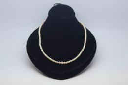 A natural saltwater pearl necklace with 10ct gold clasp set with a diamond. Accompanied with a â€