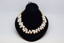 Pearl necklace, set with oval shaped pink, cream and grey pearls in an unusual design, on a yellow