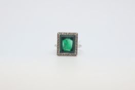 A green paste ring in a white metal mount with a halo of white stones. Size J 1/2