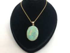 Opal pendant, oval cabochon opal measuring 22.8 x 30mm, in a yellow metal setting, on a yellow metal