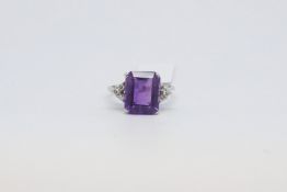 An amethyst and diamond ring. The amethyst mounted in white metal with diamond detail on the