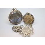 A selection of silver items including a pocket watch case, a filigree brooch and two pendants.